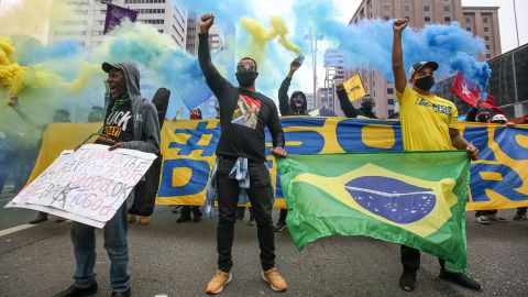 تظاهرکنندگان با ماسک صورت در خیابان پائولیستا در جریان تظاهراتی که در بحبوحه همه‌گیری ویروس کرونا (COVID-19) در 14 ژوئن 2020 در سائوپائولو، برزیل برگزار شد، مشت‌های خود را بالا می‌برند.